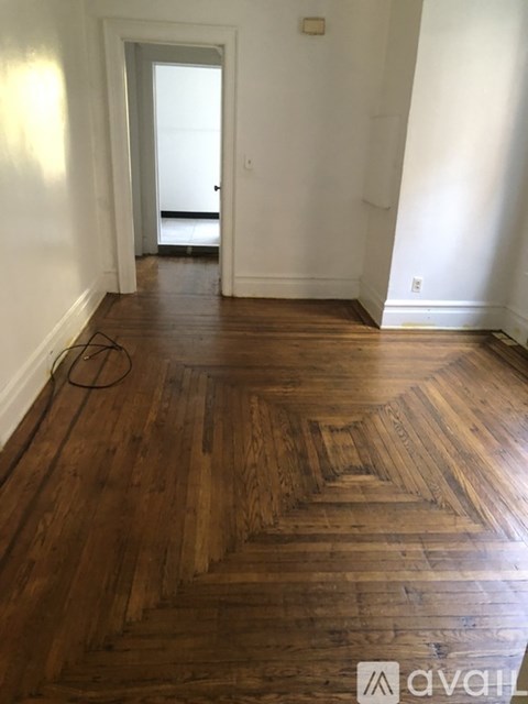 A room with wooden floors and a doorway leading to another room.