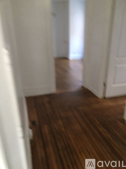 A hallway with wooden floors and white walls.