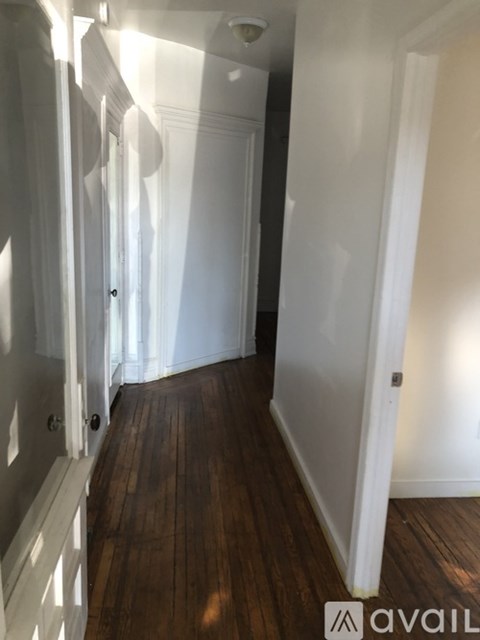 A hallway with wooden floors and white walls.