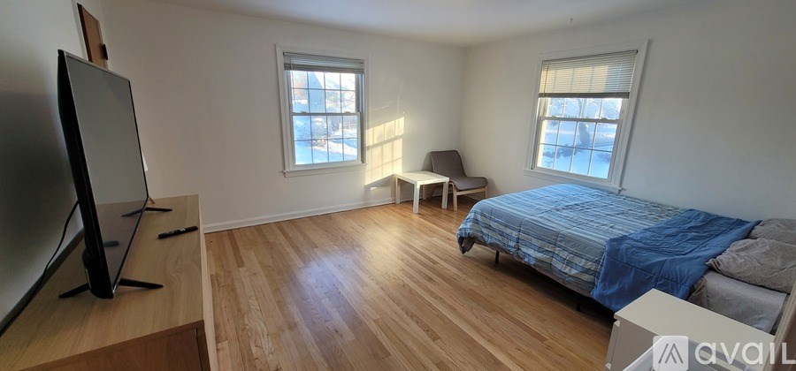 A bedroom with a bed, chair, and television.