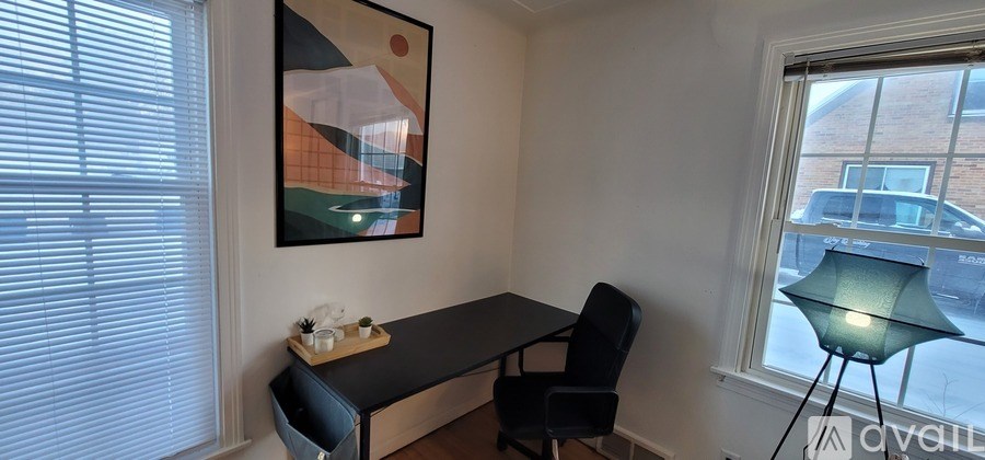 A room with a desk and a chair with a window on the left.