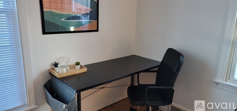 A black desk with a chair and a small table with a plant on it.