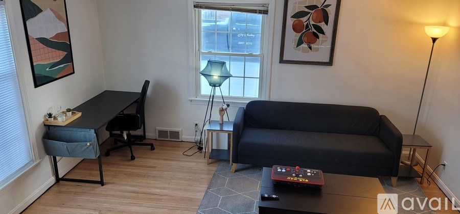 A black desk with a chair and a black couch in a room.