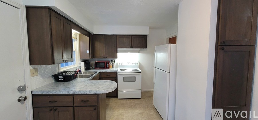 A kitchen with white appliances and brown cabinets.