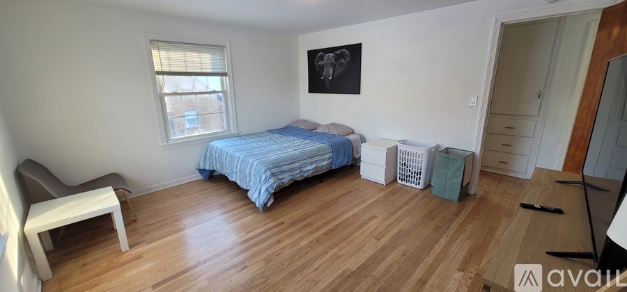 A bedroom with a bed, a chair, and a window.