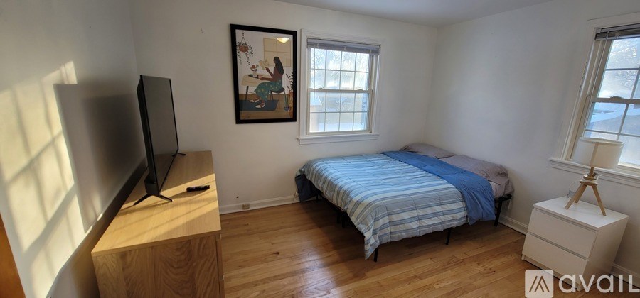 A bedroom with a bed, a television, and a painting on the wall.