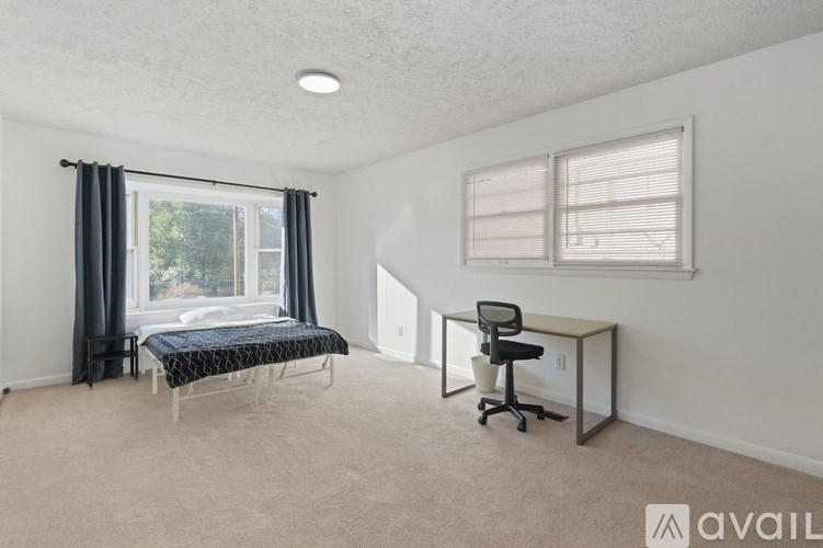 A bedroom with a bed, desk, and chair.