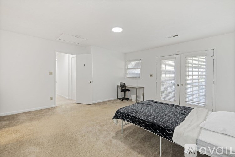 A bedroom with a bed, desk, and chair.