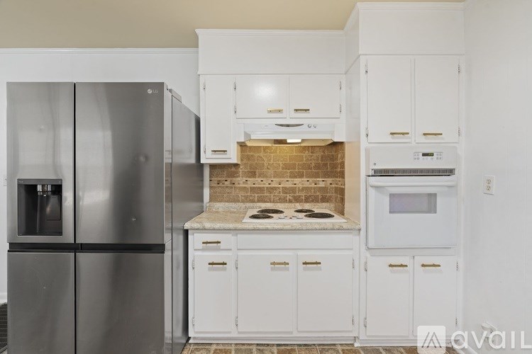 A modern kitchen with white cabinets and a stainless steel refrigerator.