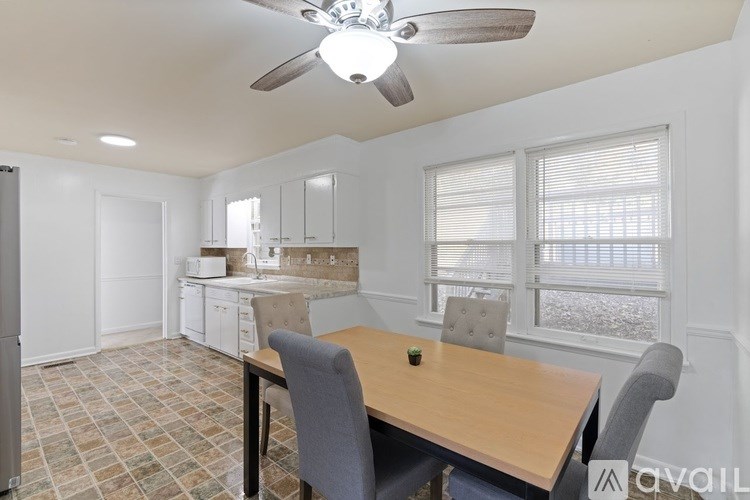 A kitchen with a table and chairs in the foreground and a refrigerator in the background.