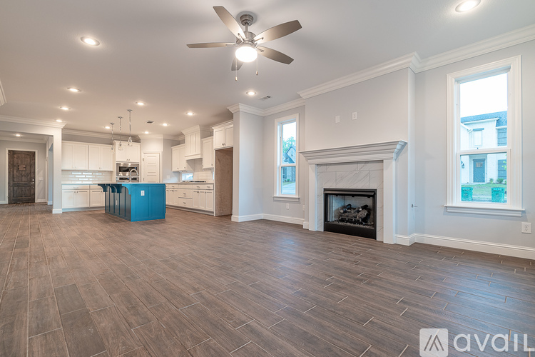 A spacious living room with a fireplace and a ceiling fan.
