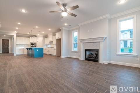 A spacious living room with a fireplace and a ceiling fan.