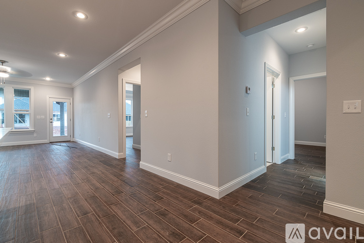 A spacious room with wood flooring and white walls.