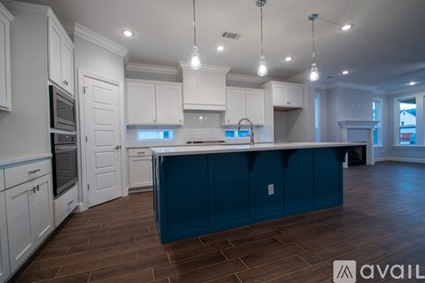 A kitchen with white cabinets and a blue island.