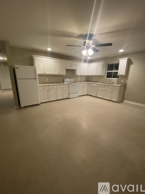 A spacious kitchen with white appliances and cabinets.