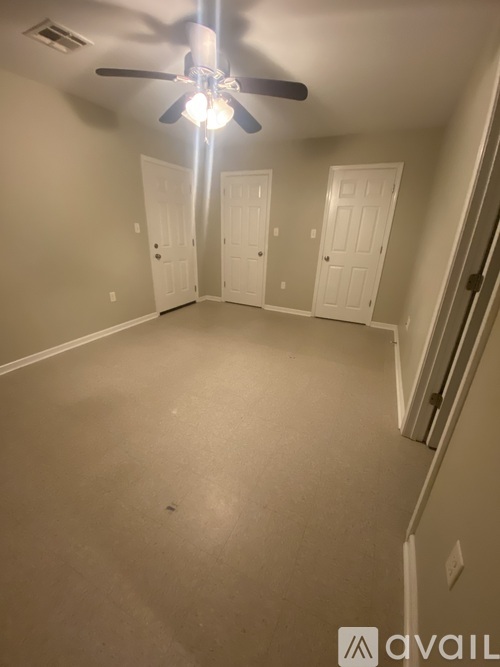 A room with a ceiling fan and white doors.
