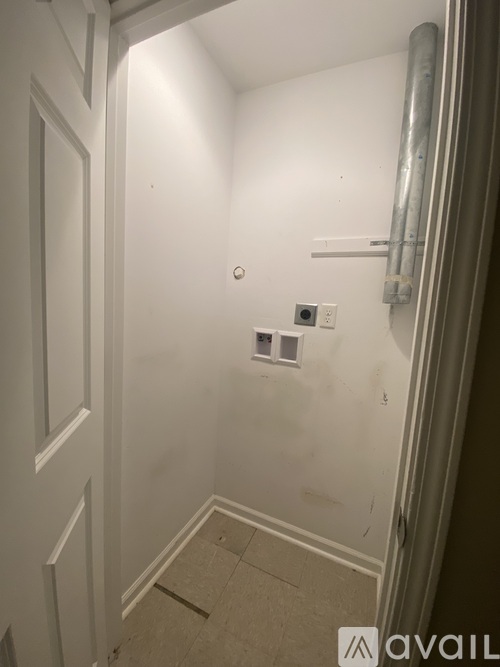 A bathroom with a white door and a white wall.