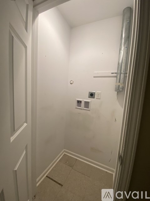 A bathroom with a white door and a white wall.