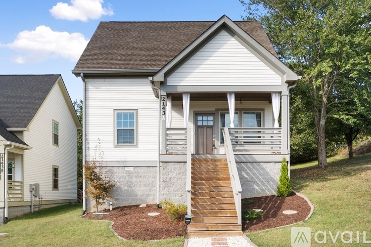 A two-story house with a front porch and a brown roof.