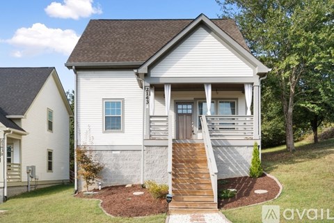 A two-story house with a front porch and a brown roof.
