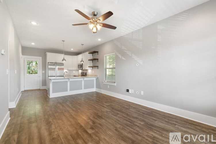 A spacious room with a ceiling fan and wooden flooring.
