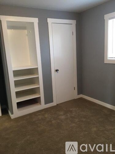 A room with a white door and a white shelving unit.