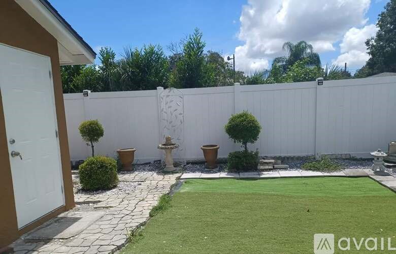 A backyard with a white fence, a small garden, and a white door.