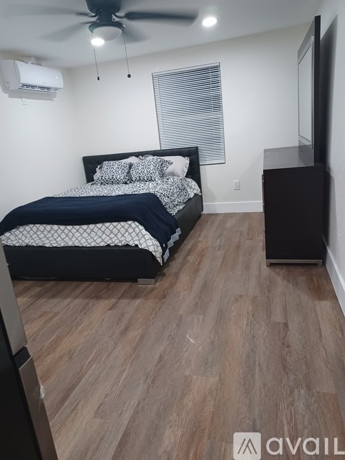 A bedroom with a bed, a ceiling fan, and a television.