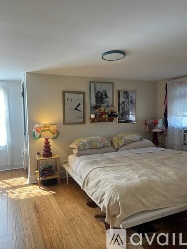 A bedroom with a bed, nightstand, and pictures on the wall.