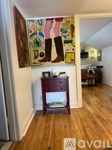 A room with a wooden floor and a painting of a boot on the wall.