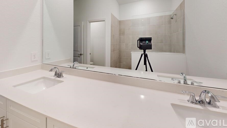 A bathroom with a white countertop and a camera on a tripod.