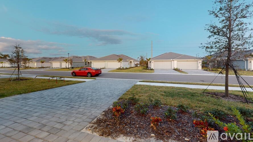 A red car is parked on a driveway in front of a house.