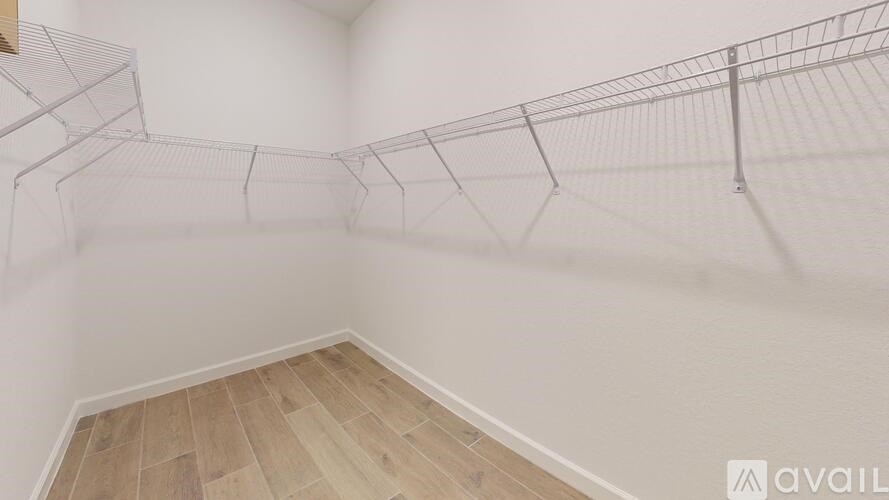 A room with a wooden floor and a white wall with a wire mesh on the ceiling.