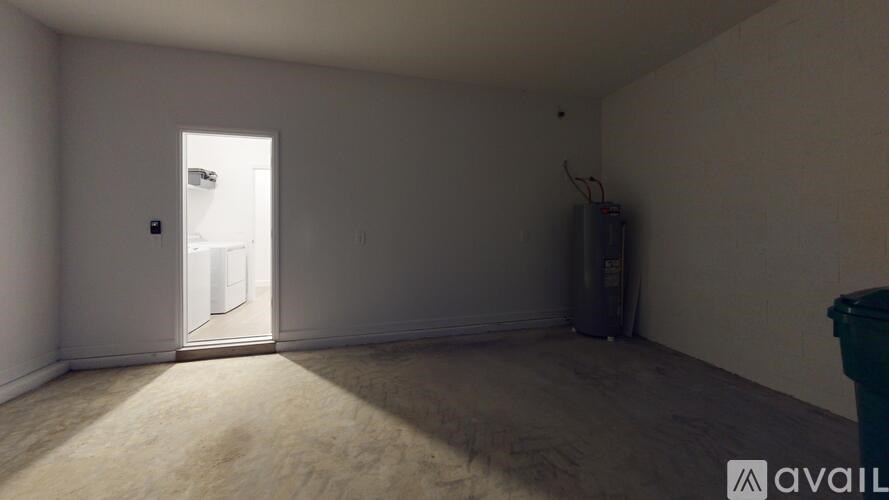 A room with a door and a trash can.