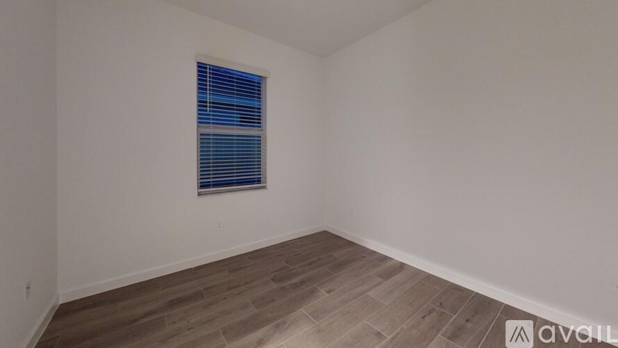 A room with a window and wooden flooring.