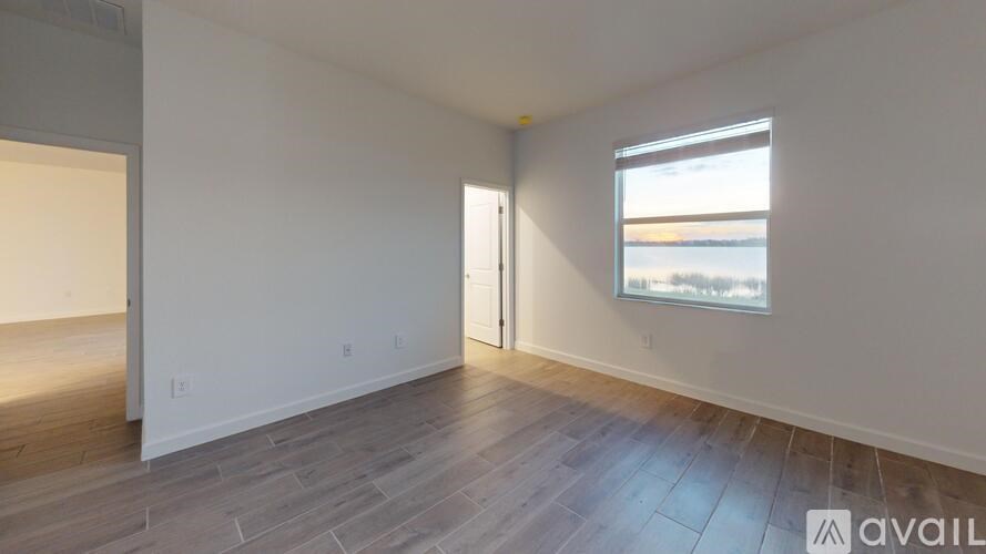 A room with wooden flooring and a window overlooking the beach.