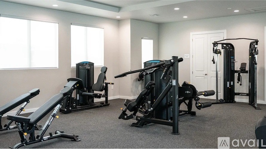 A gym with a variety of equipment including a leg press machine, a chest press machine, and a leg curl machine.