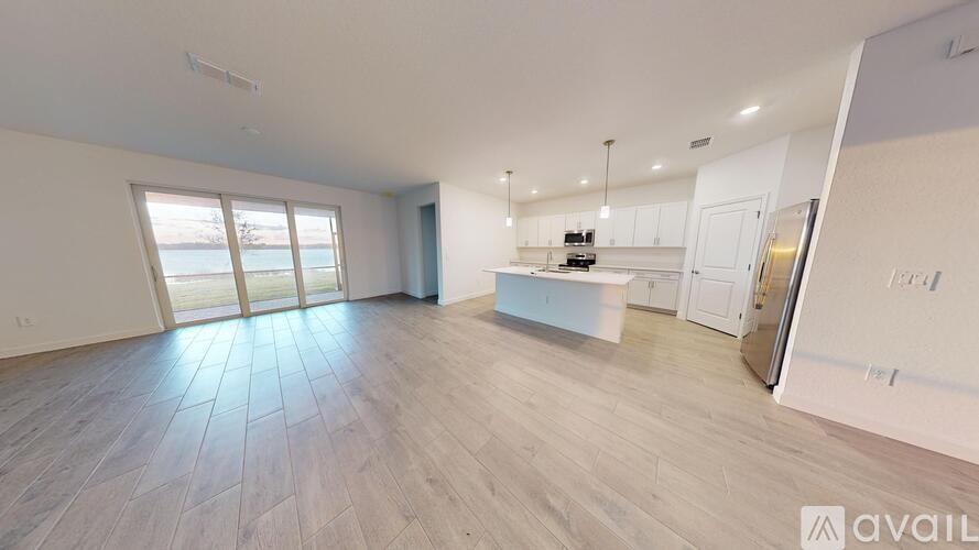 A spacious living area with a kitchen in the background.