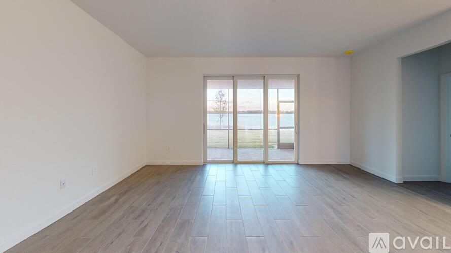 A room with wooden flooring and a large window with a view of the outside.