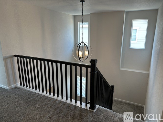 A room with a carpeted floor, a chandelier, and a window.