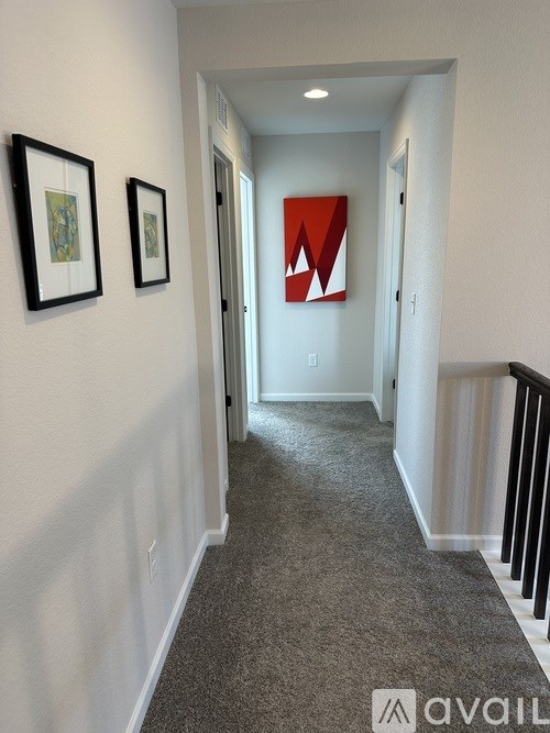 A hallway with a carpeted floor, two framed pictures on the wall, and a red letter "W" on the wall.