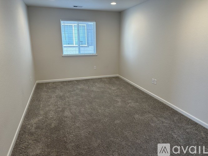 A room with a carpeted floor and a window with blinds.