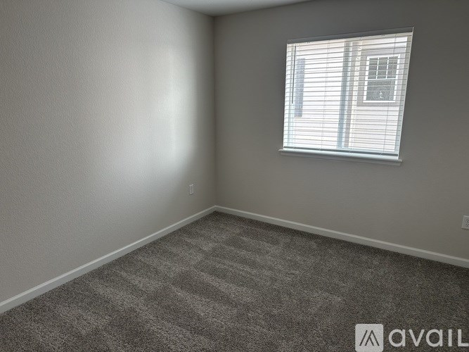 A room with a carpeted floor and a window with blinds.
