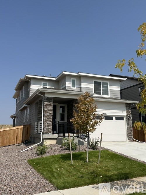 A modern house with a grey and white exterior and a black garage door.