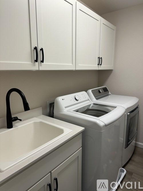 A white sink and a white washing machine in a small laundry room.