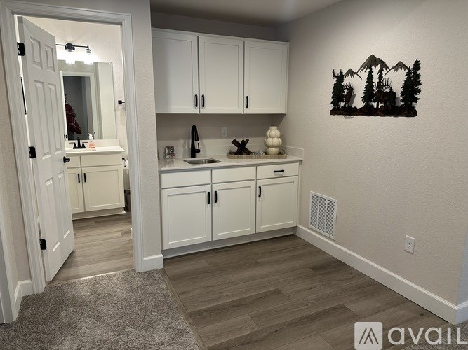 A kitchen with white cabinets and a wooden floor.