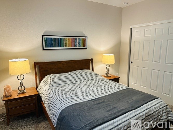 A bedroom with a bed, nightstands, and a painting on the wall.