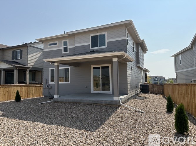 A modern house with a grey and white exterior and a gravel driveway.
