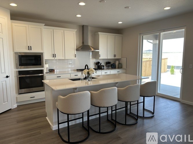 A kitchen with white cabinets and a large island with four chairs.