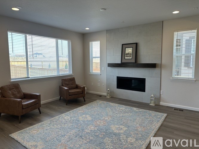 A living room with a fireplace and two chairs.